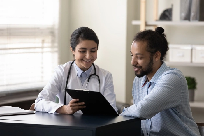 Happy young indian female gp doctor showing test result on clipboard