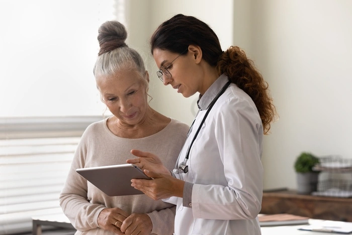 doctor showing tablet screen to old 70s female patient